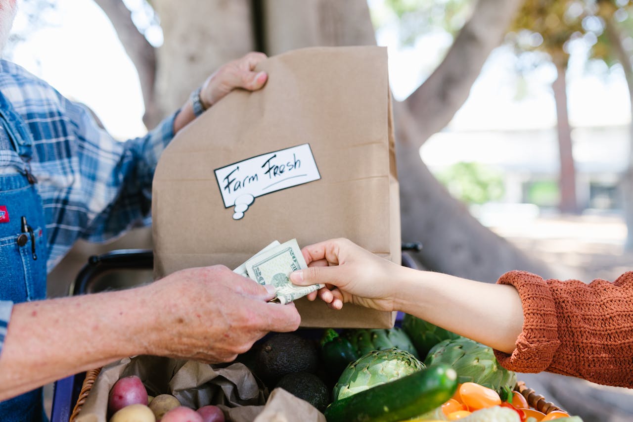 our-services-2 Close-up of a transaction at a farmer's market with fresh produce.